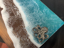 Load image into Gallery viewer, Live Edge Walnut, rich browns and warm golds, food safe epoxy covering 80% of wood in a wave pattern white, clear, teal blue with octopus handles.

