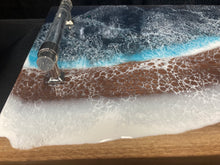 Load image into Gallery viewer, Live Edge Walnut, rich browns and warm golds, food safe epoxy covering 90% of wood in a wave pattern white, clear, light and dark blues with clear tube handles.
